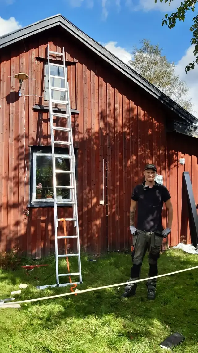 Marcus, snickare på Hederligt Hantverk, framför en röd lada på Österlen